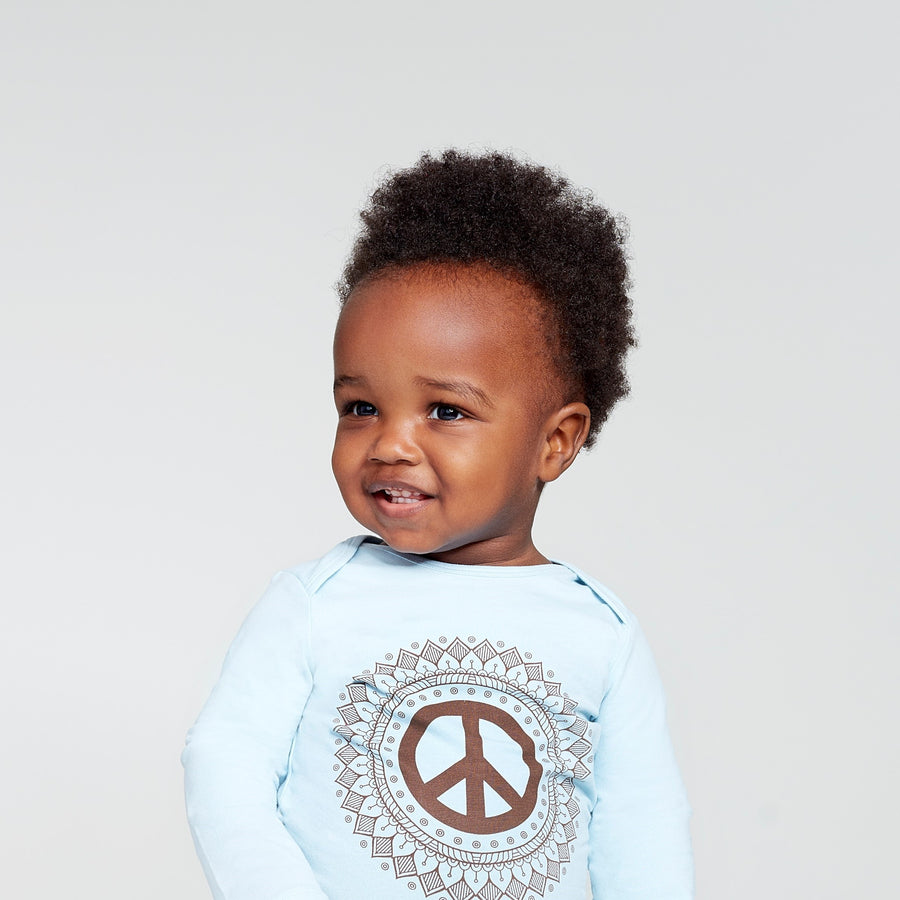 Happy baby wearing long sleeve onesie with peace sign print