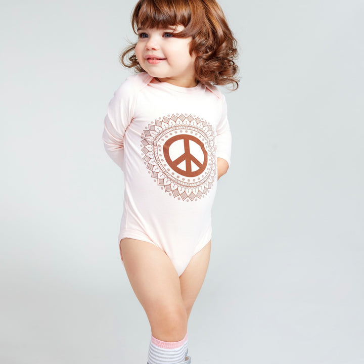 Baby girl wearing a pink long sleeve baby onesie with peace sign print