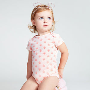 Baby girl wearing a pink short sleeve onesie with lotus flower print