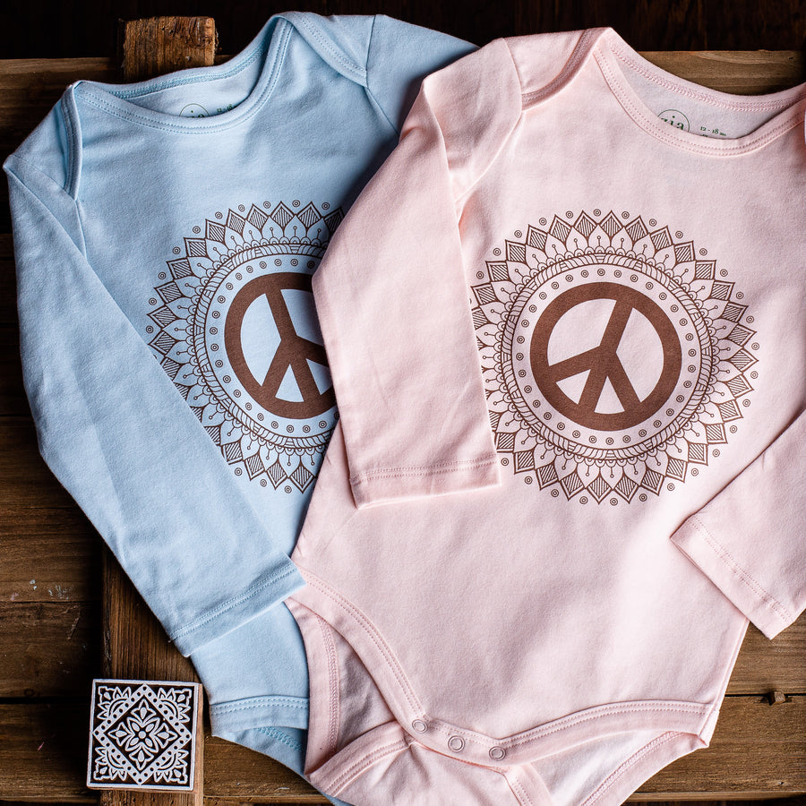 Two long sleeve baby onesies in blue and pink with peace sign print