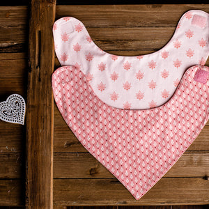Pink bib with lotus flower print and pink bib with leaf print on wooden background