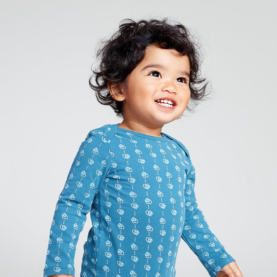 Happy baby wearing blue long sleeve onesie with printed hearts 