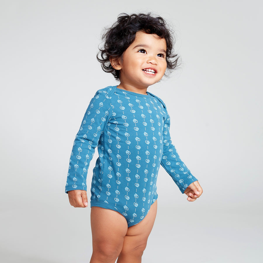 Happy baby wearing a blue long sleeve onesie with heart print