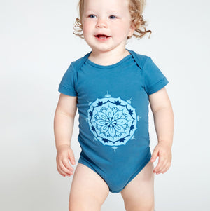 Happy baby wearing a blue short sleeve onesie with mandala print