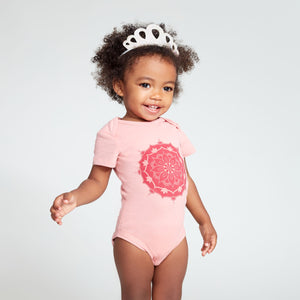 Baby girl wearing a pink short sleeve onesie with a large mandala print